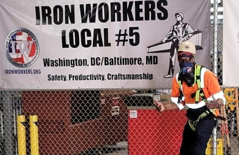 John stands in front of an iron workers local #5 sign in his work outfit